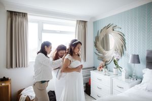Wedding preparations in a bright bedroom with floral wallpaper and decorative mirror.