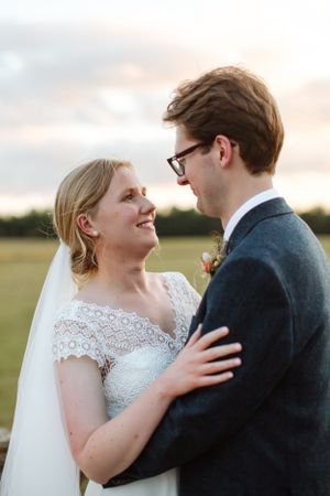 Bride and groom share an intimate moment during sunset in their wedding attire.