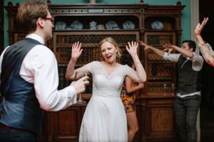 A lively dance scene at a wedding reception with people celebrating in formal attire.