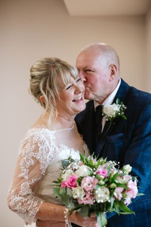 Wedding couple sharing tender moment with pink and white floral bouquet.