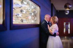 Intimate moment between couple against purple walls with artwork and mood lighting.