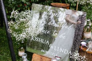 Clear acrylic wedding welcome sign decorated with baby's breath flowers.