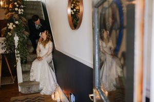 Wedding dress reflection in mirror with romantic venue decor and floral arrangements.