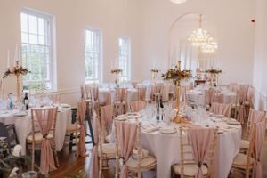 Elegant wedding reception room with blush chair covers and crystal chandeliers.