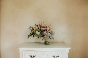 Elegant floral arrangement with pink and white blooms on vintage white dresser.