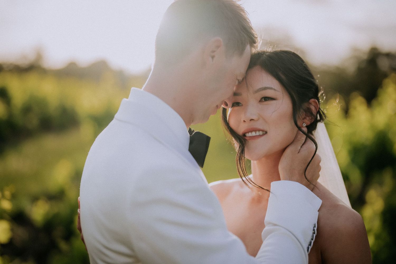 An intimate wedding moment shared against a sunlit natural backdrop.