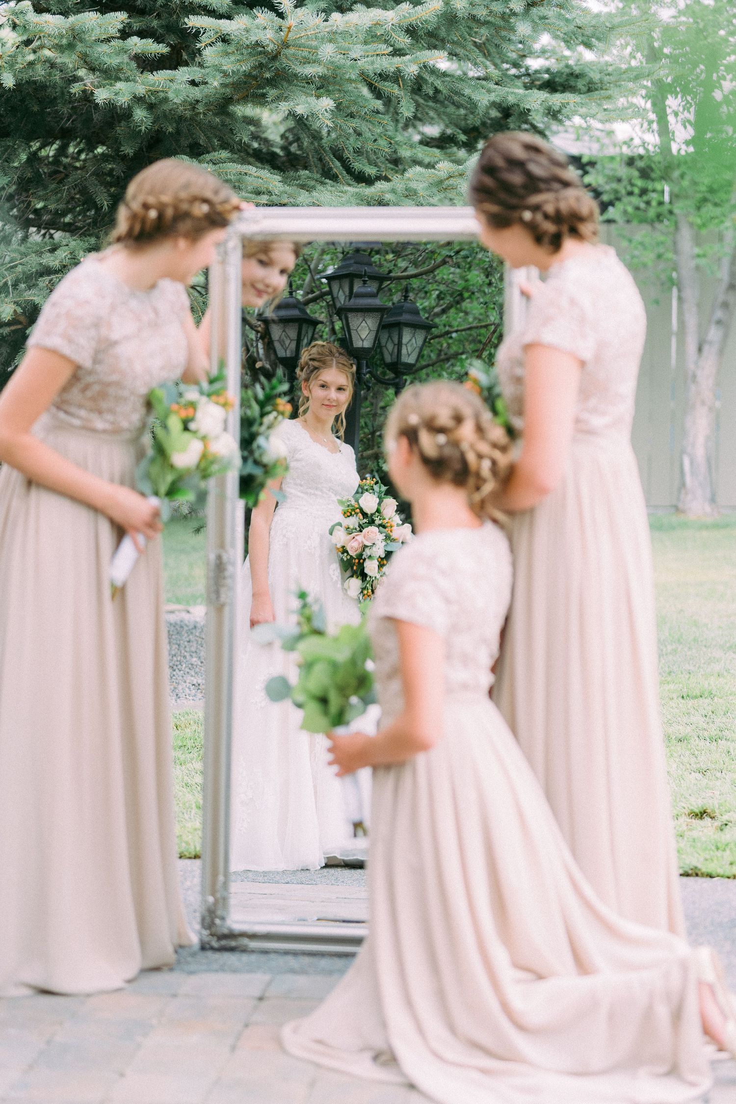 Artistic wedding photo with ornate mirror reflection and bridesmaids in blush pink dresses.