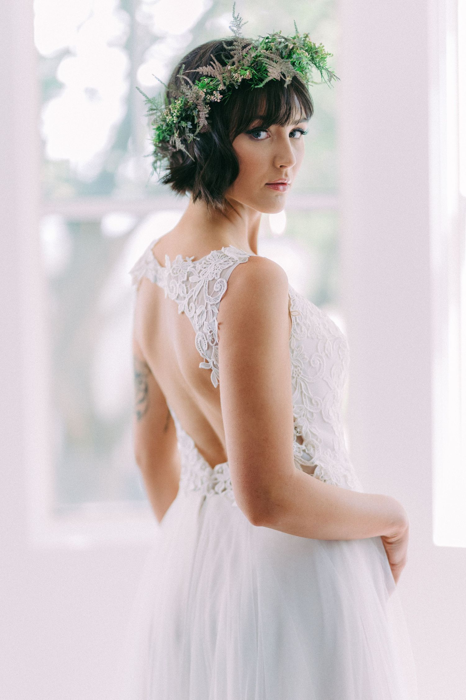 Delicate lace wedding dress with open back design and floral crown detail.