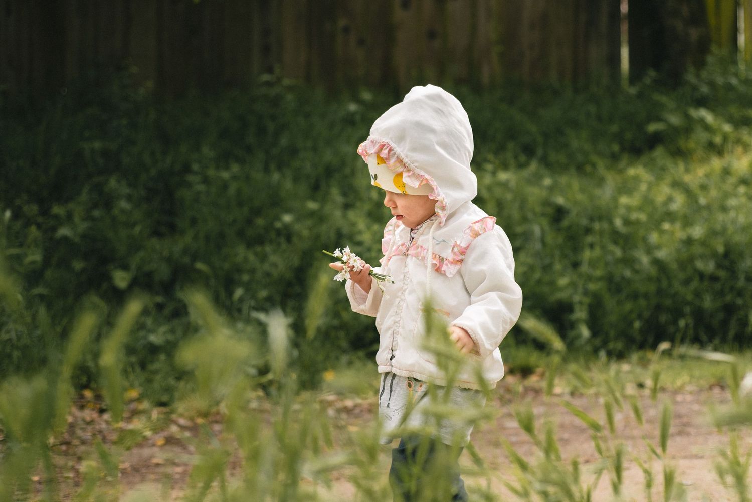 Child in white winter clothing playing outdoors in a natural setting.
