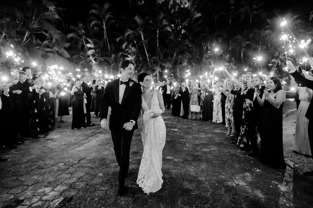 Bride and groom leave the reception, lit by sparklers.