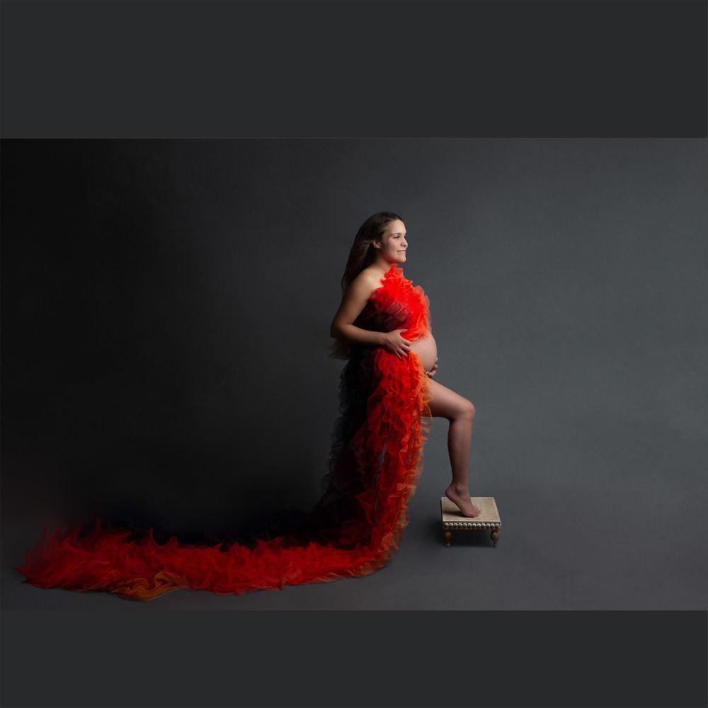 beautiful pregnant woman in flowing red dress posing for maternity photographs