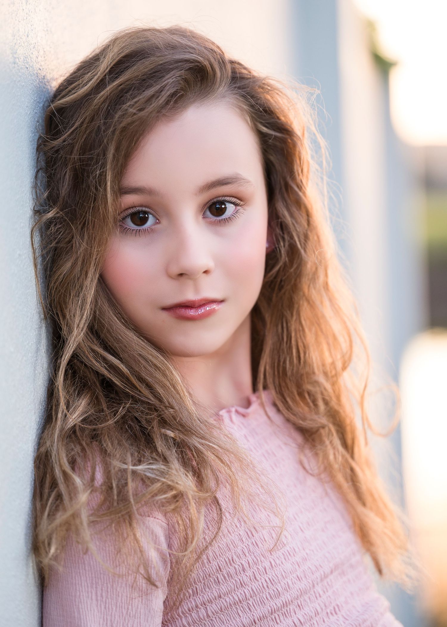 Portrait against white wall with soft lighting and pink top.
