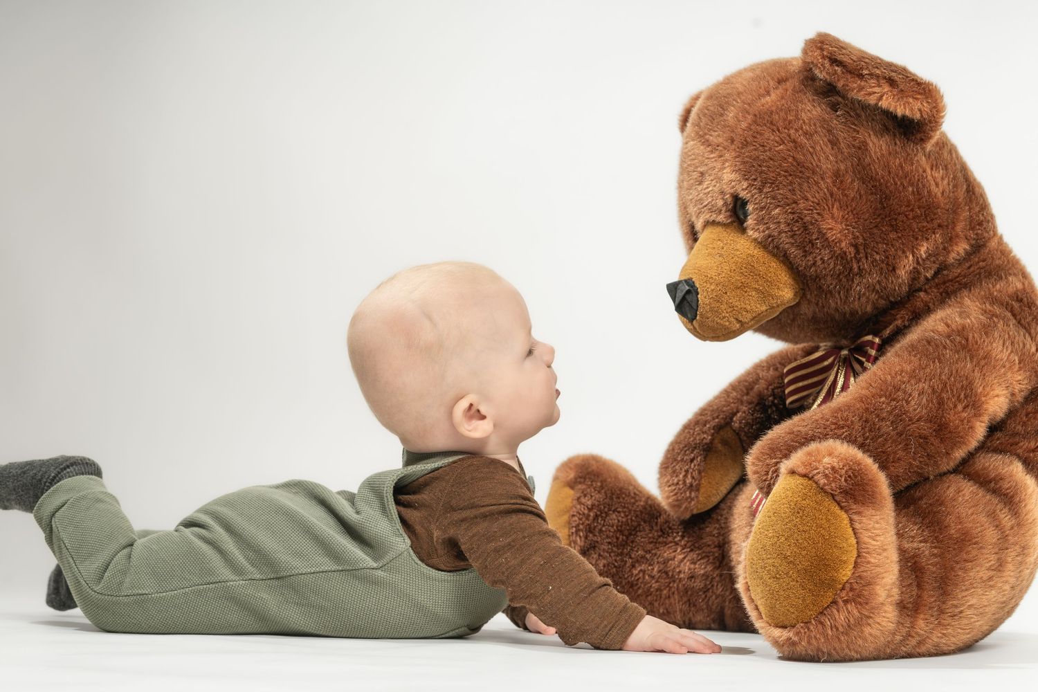 Baby fotograferet i studie i Jægerspris, legende med stor bamse. Kreative baby- og familieportrætter for familier i Frederikssund