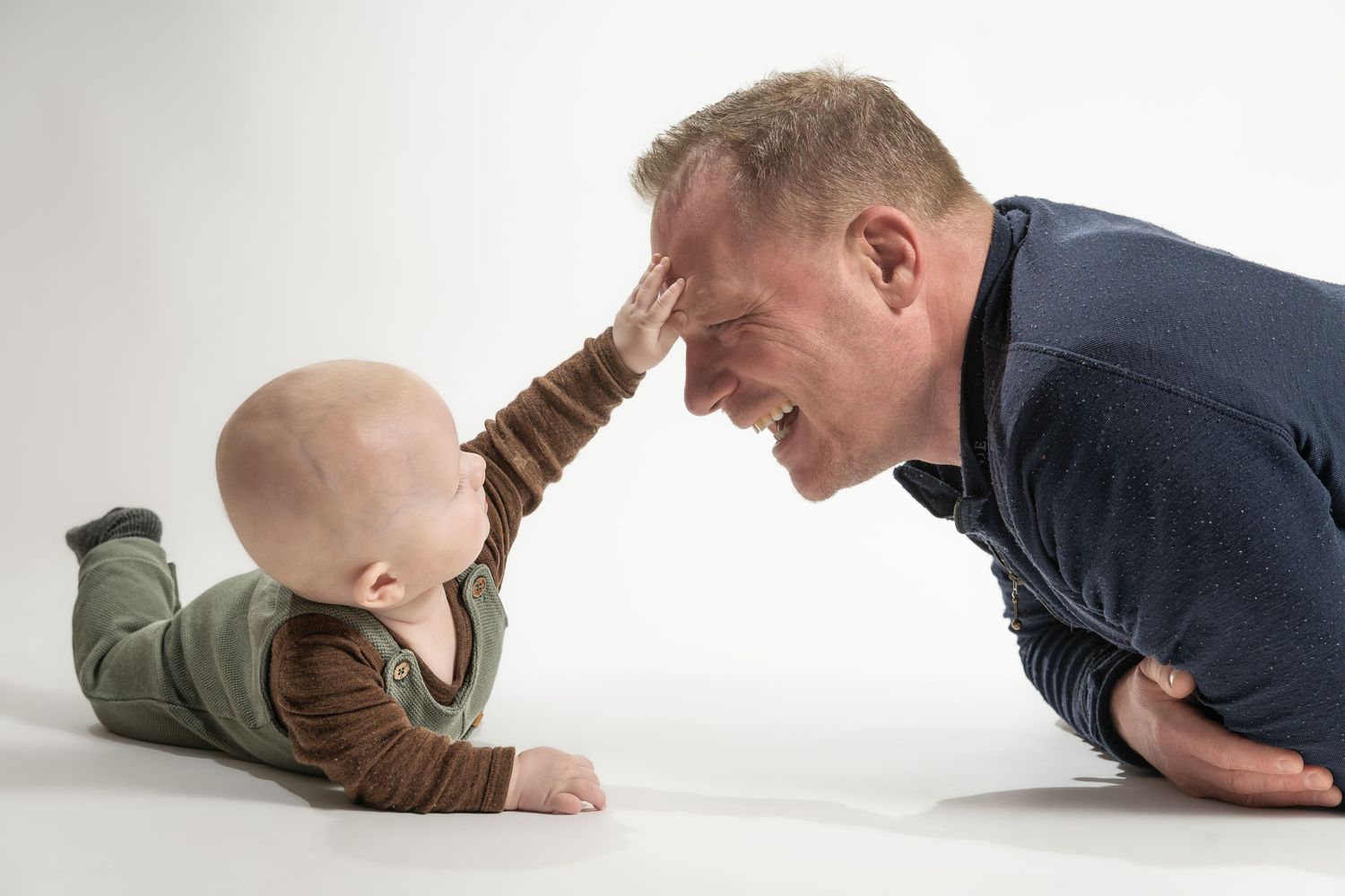 Far og baby leger under studie-fotografering hos fotograf i Jægerspris. Naturlige familie- og babybilleder for familier i Frederikssund
