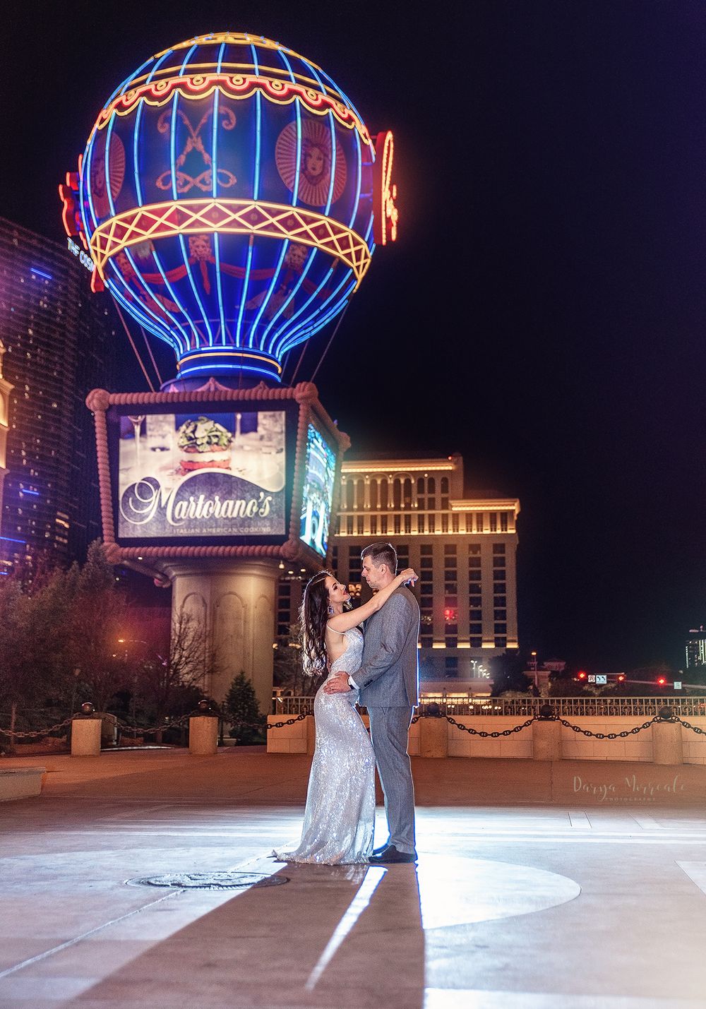 Couple posing beneath the iconic Paris Las Vegas balloon sign at night.
