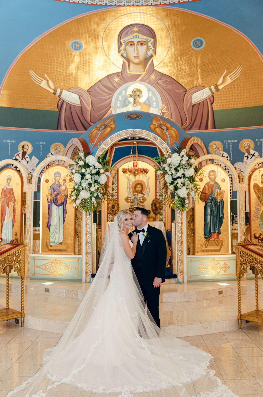 Orthodox church wedding ceremony with stunning gold iconostasis and religious artwork in background.