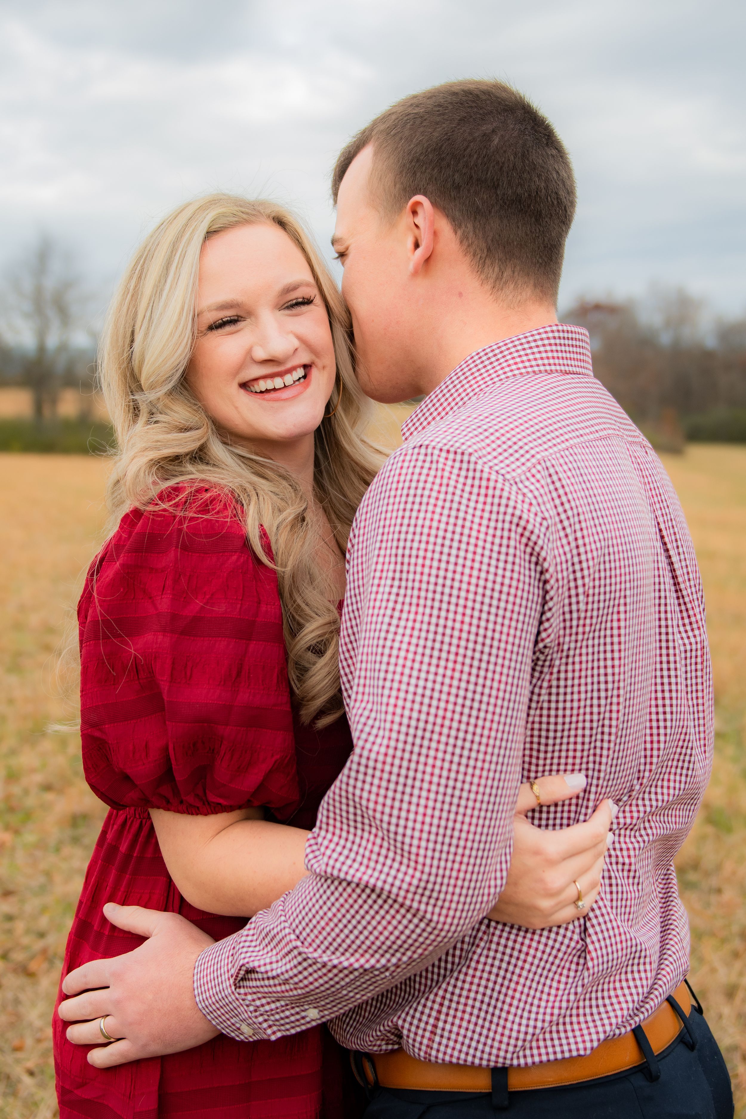 A couple embraces in a field during an engagement photoshoot.