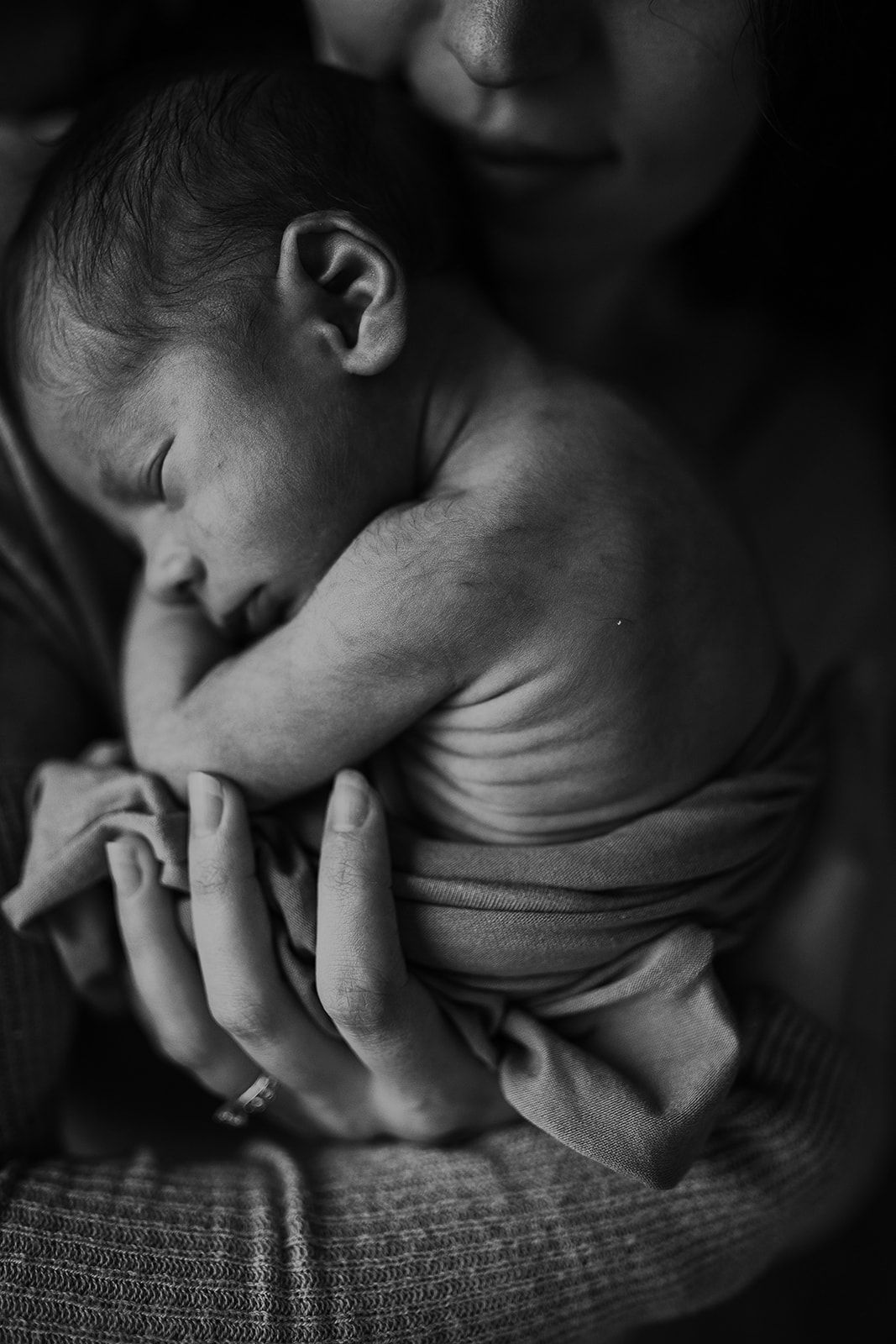 A black and white image of a mother holding her son while showcasing his wrinkly newborn skin.