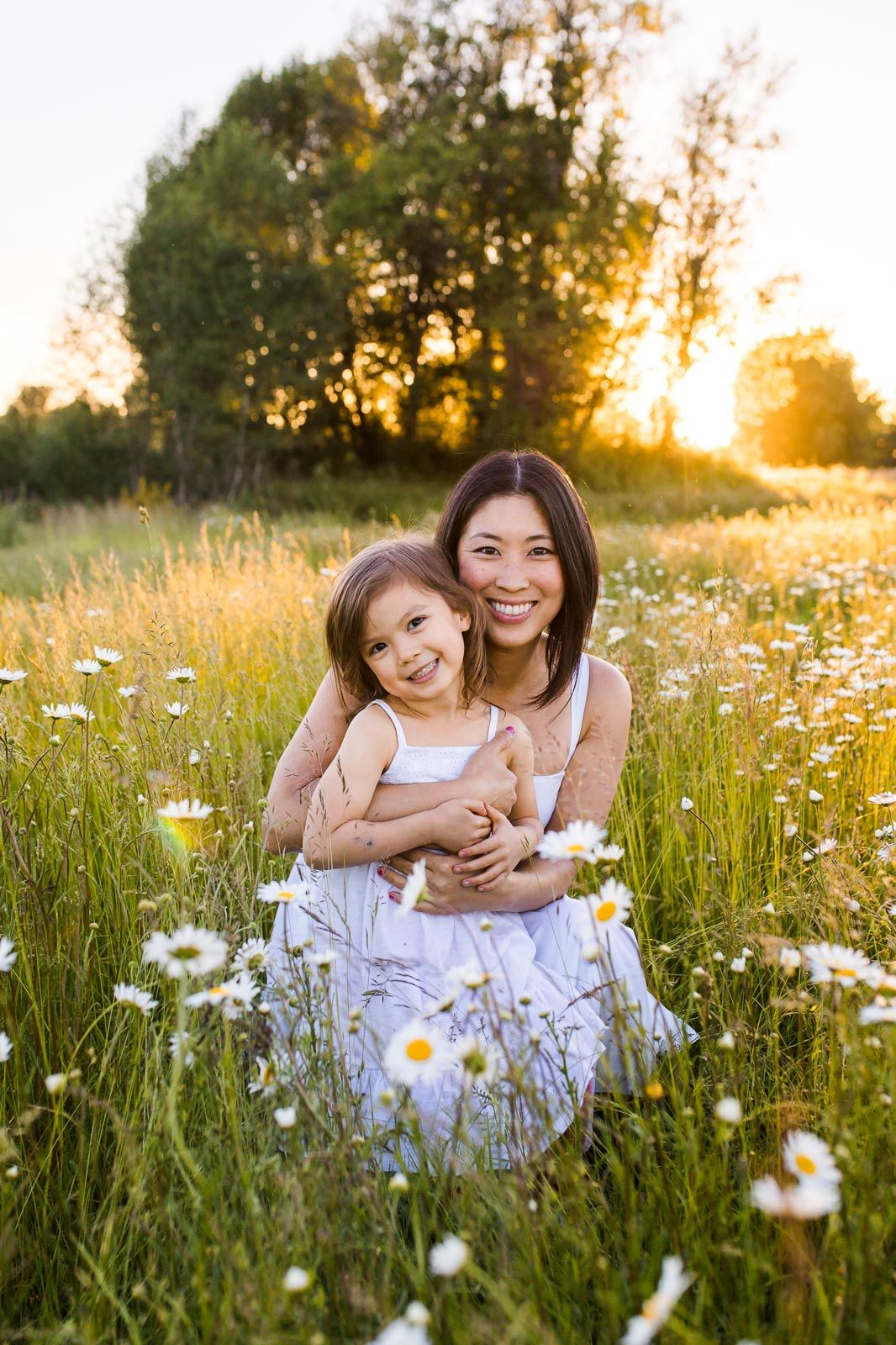 Mother daughter cuddling in a daisy field in Redmond