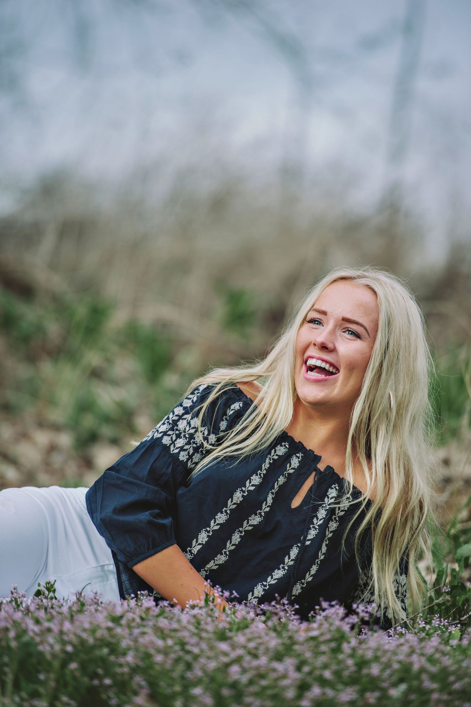 A blonde girl laughs in a field of purple flowers