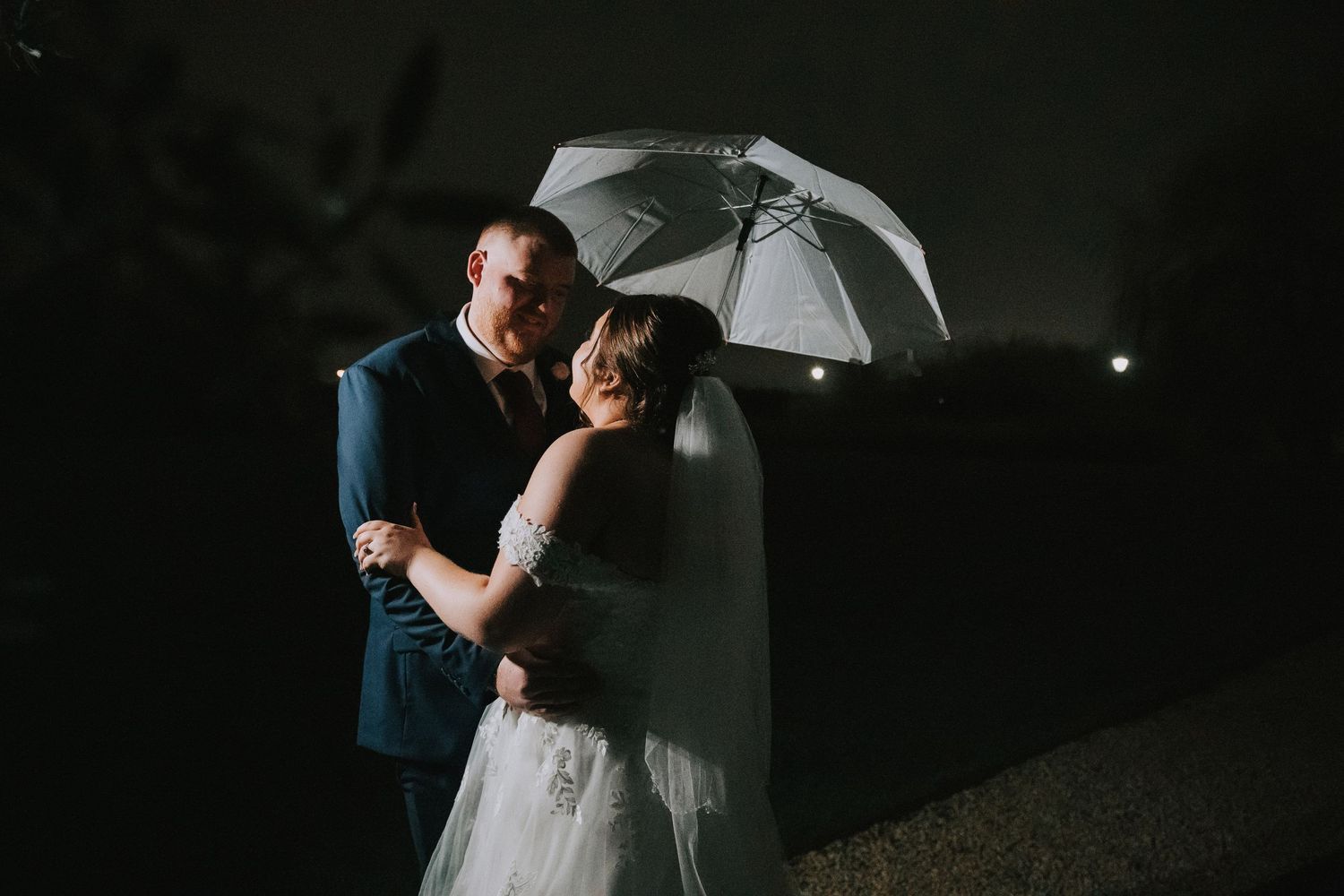 bride and groom at their twilight wedding posed with white umbrella