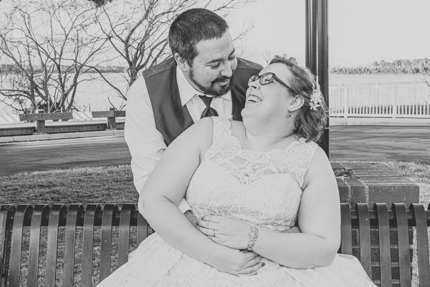 Black and white romantic wedding portrait of couple on park bench.