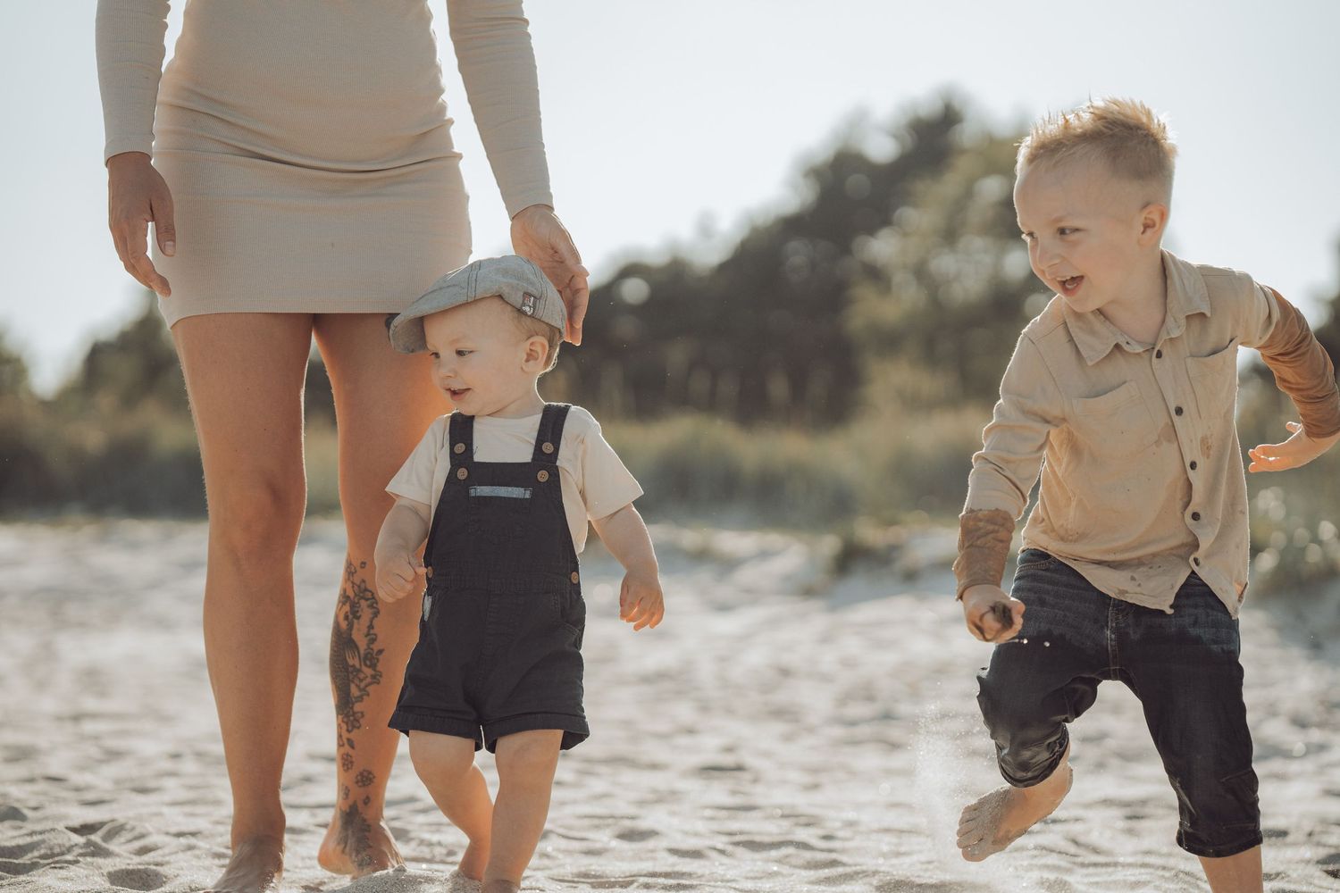Familj som leker på stranden två pojkar och en mamma