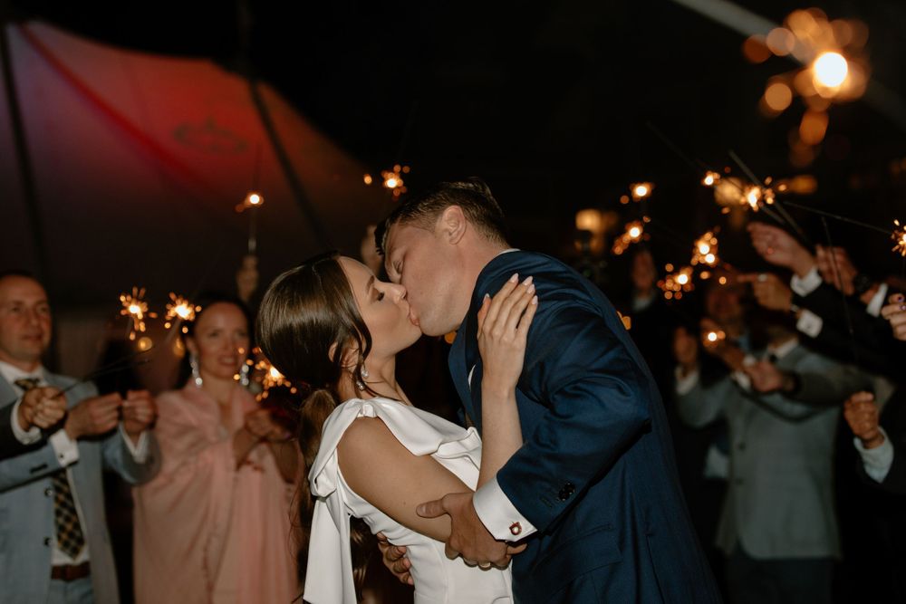 Couple shares romantic kiss during sparkler exit at their wedding reception.