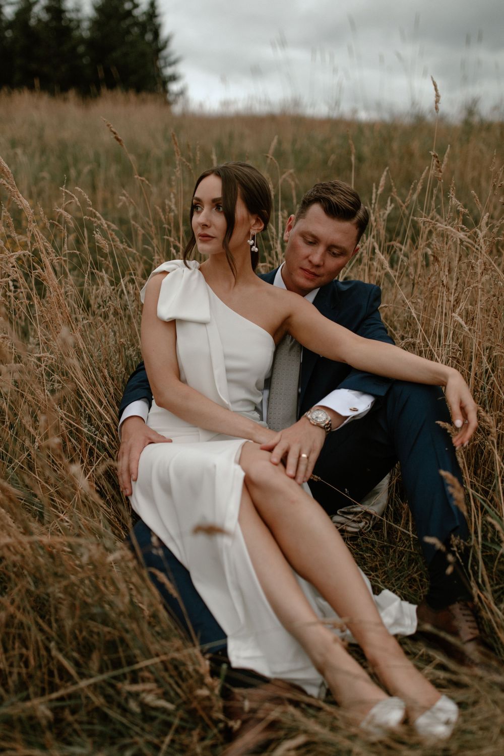 Intimate couple moment captured in tall grass field during sunset.