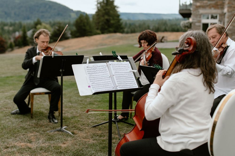 Musicians perform classical music outdoors during mountain wedding ceremony.