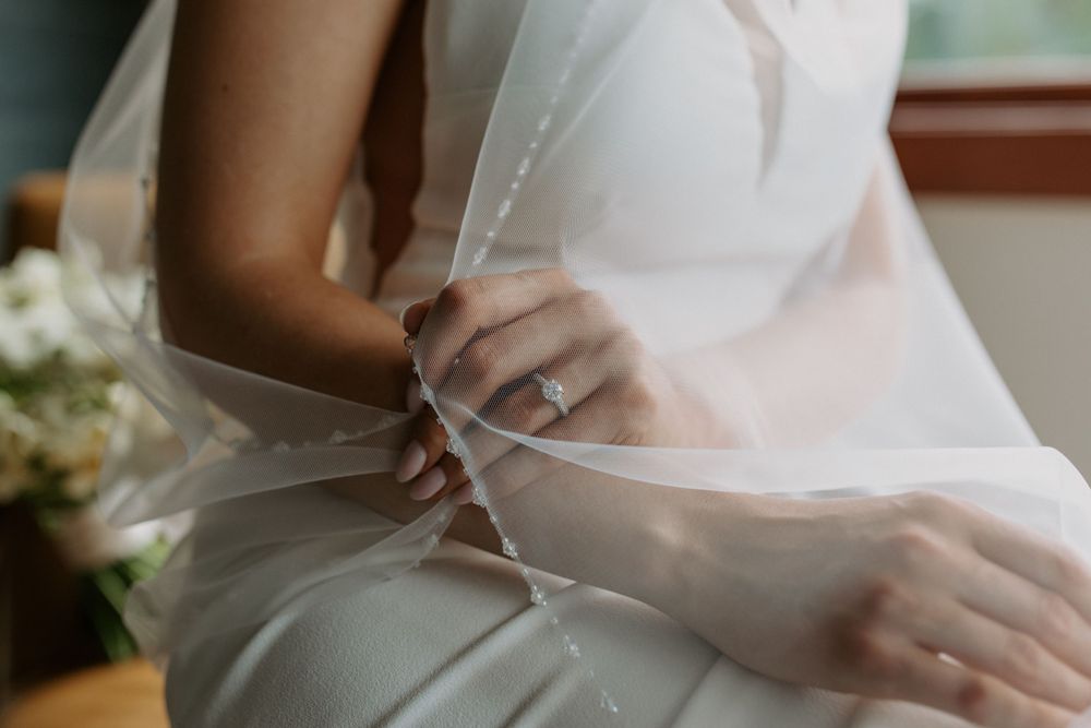 Close-up detail of hands adjusting a white wedding dress.