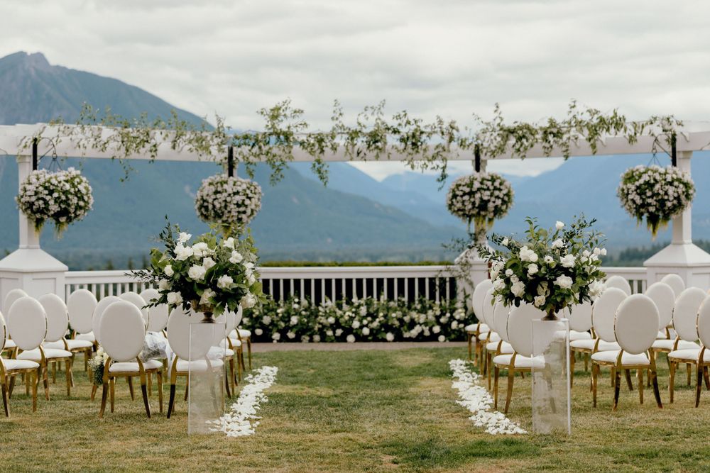 Elegant outdoor wedding ceremony setup with floral arch and mountain views.