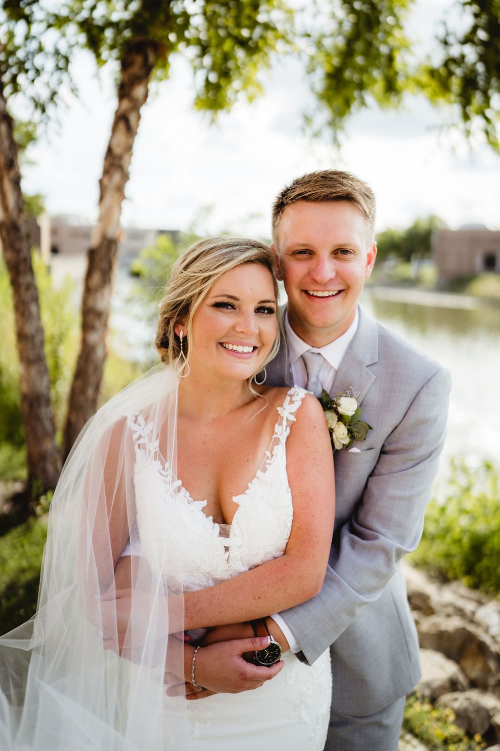Romantic wedding portrait by lake with willow trees in background.