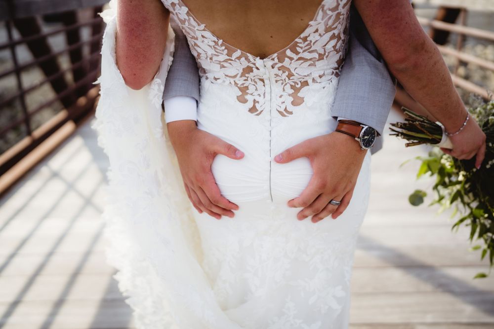 Close-up detail of a white lace wedding dress back and hands.