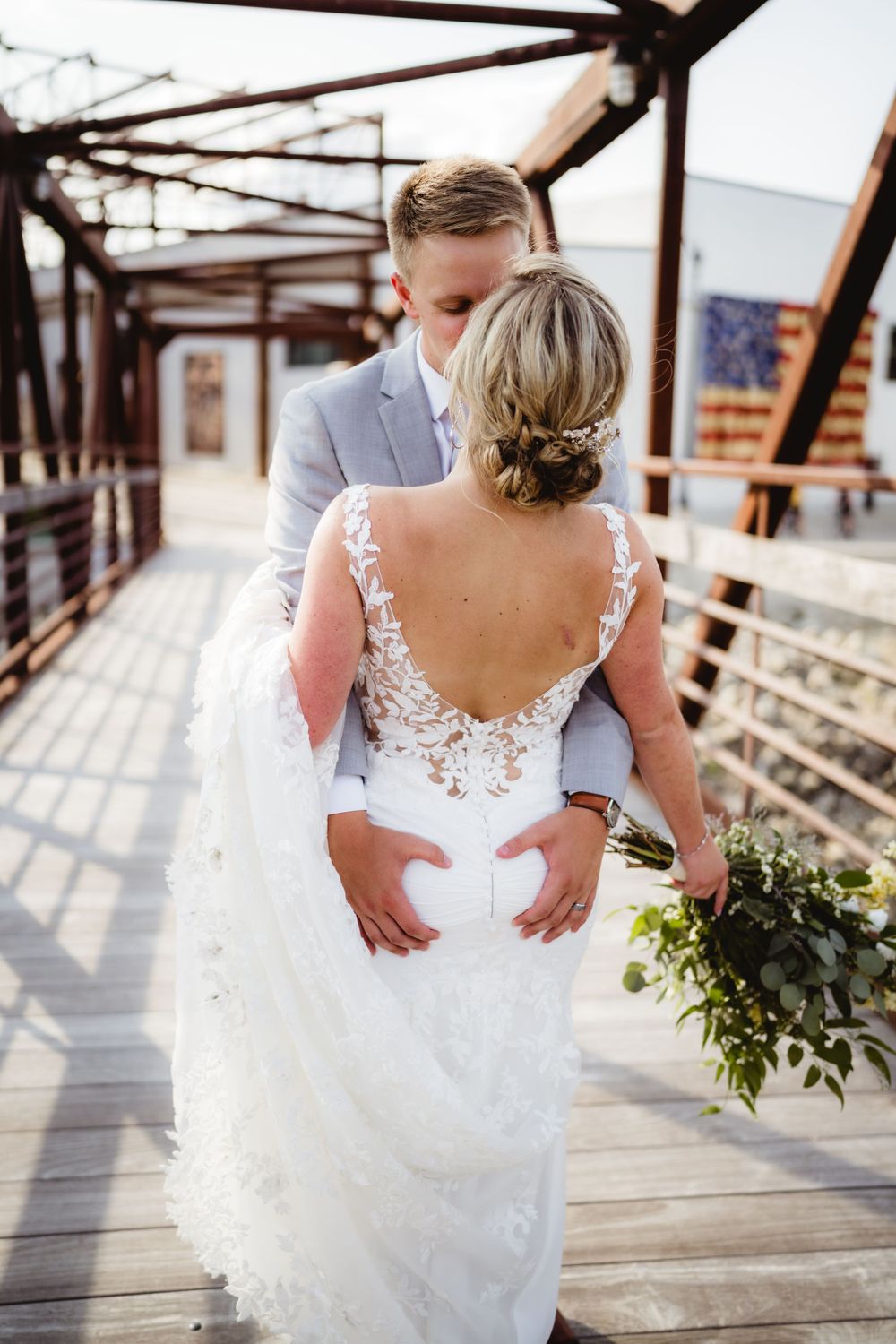 Romantic moment captured on industrial bridge with lace dress details.