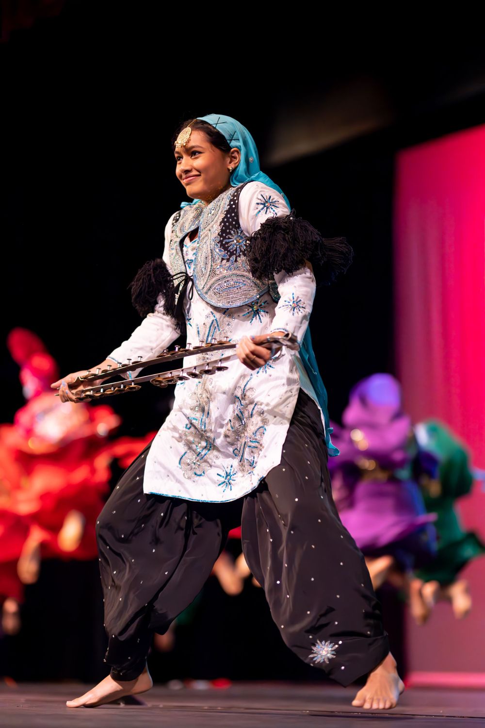 Dancer in ornate white and blue costume performs traditional dance moves on stage.