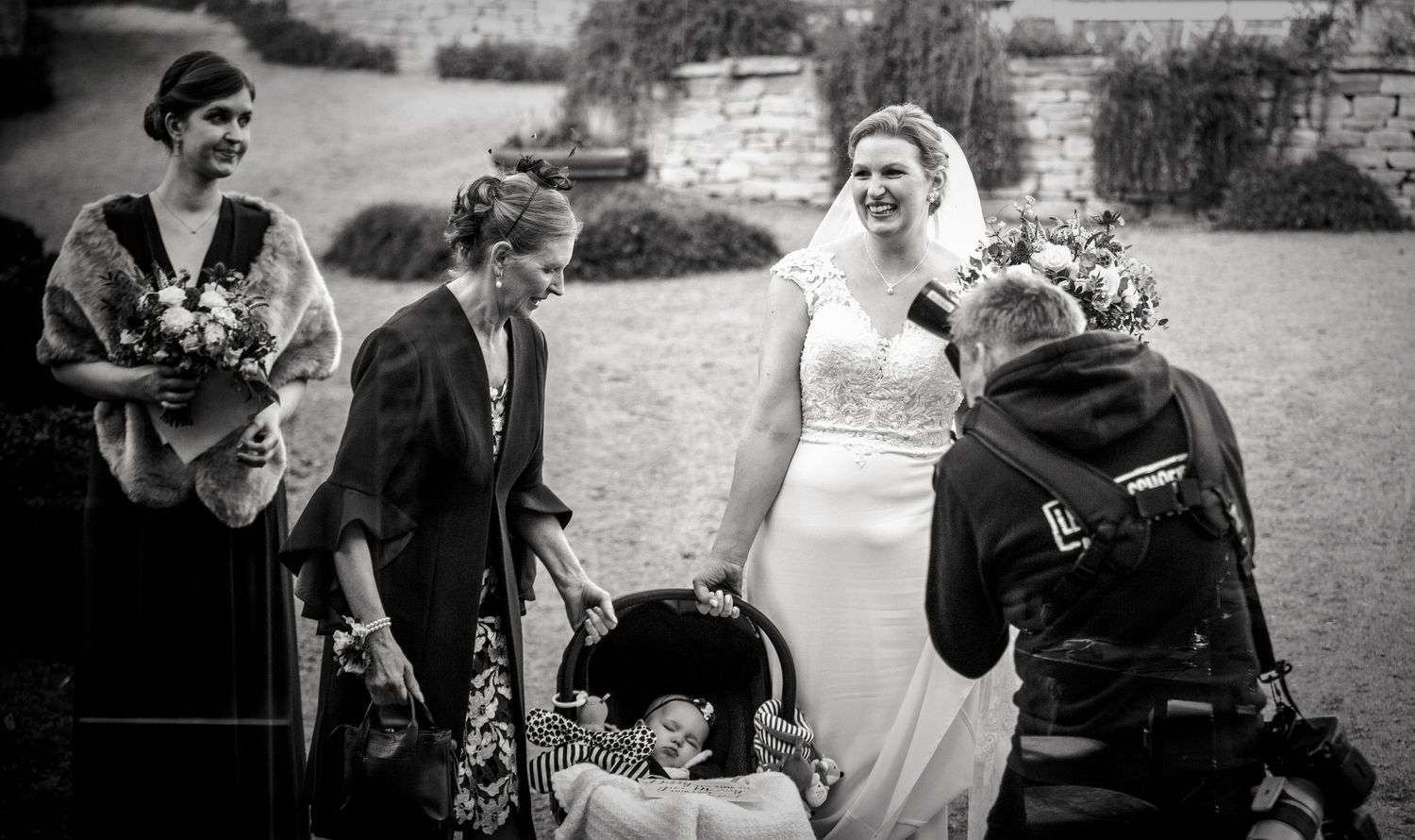 Outdoor black and white wedding photography with guests gathered in a natural setting.