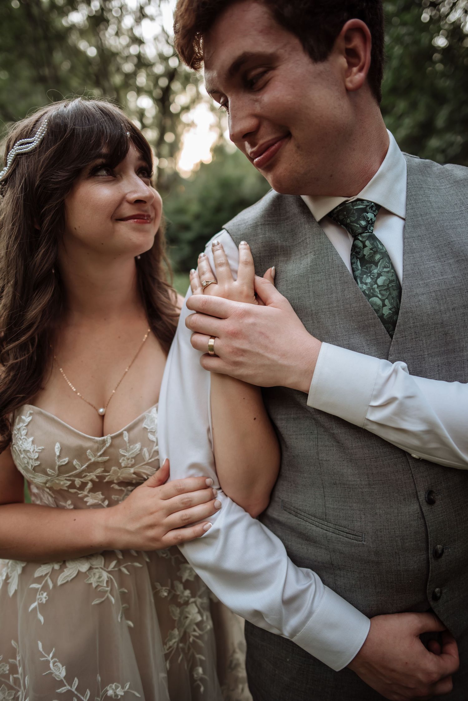 A couple shares an intimate moment at their wedding, with the bride in a floral gown and groom in gray suit.