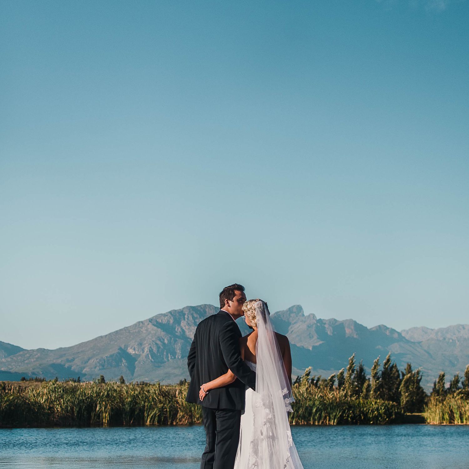 bride and groom with the dam and picturesque mountains in the background