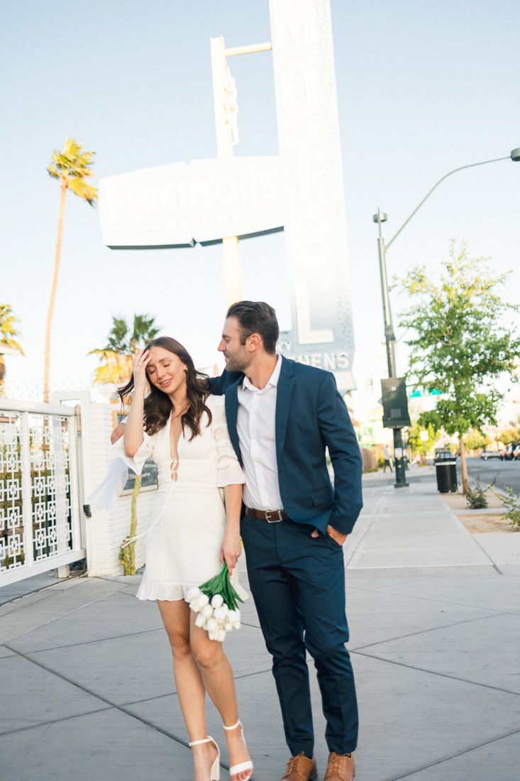 Couple sharing a laugh while walking together on urban sidewalk with modern architecture.