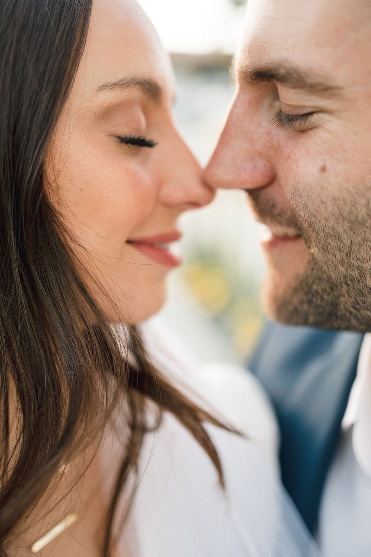 A romantic close-up moment between a couple in white and navy attire.