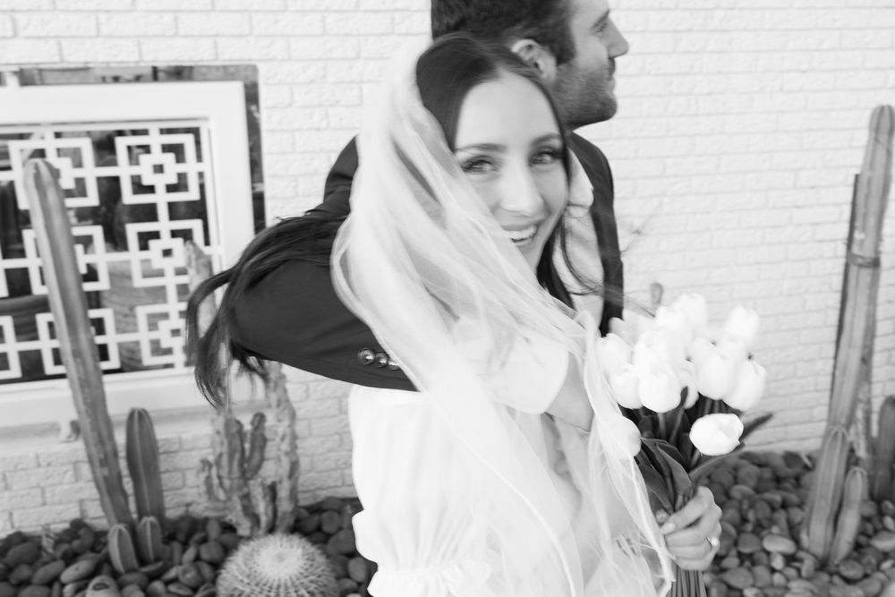 A black and white portrait of someone in a flowing veil holding white flowers.