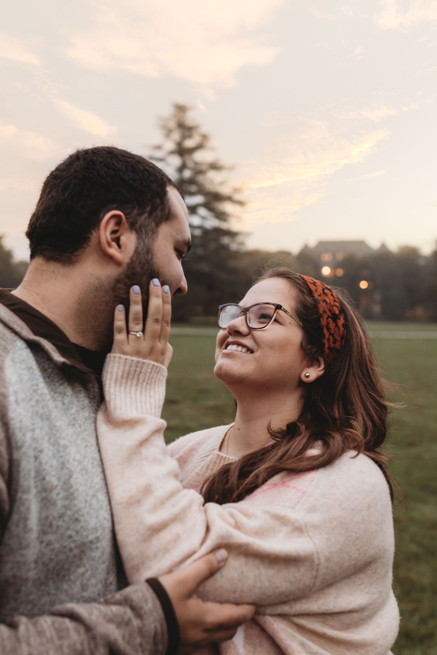 A couple sharing an intimate moment and laughing together outdoors during sunset.