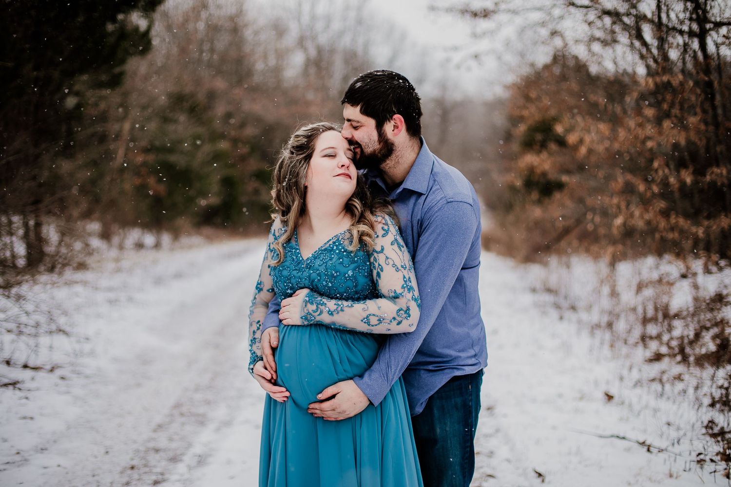 Winter engagement photos of couple in blue attire against snowy landscape.