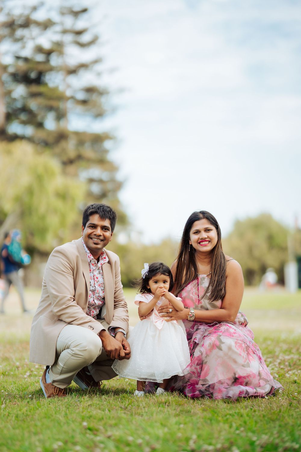 Family portrait on grass with toddler in white dress.