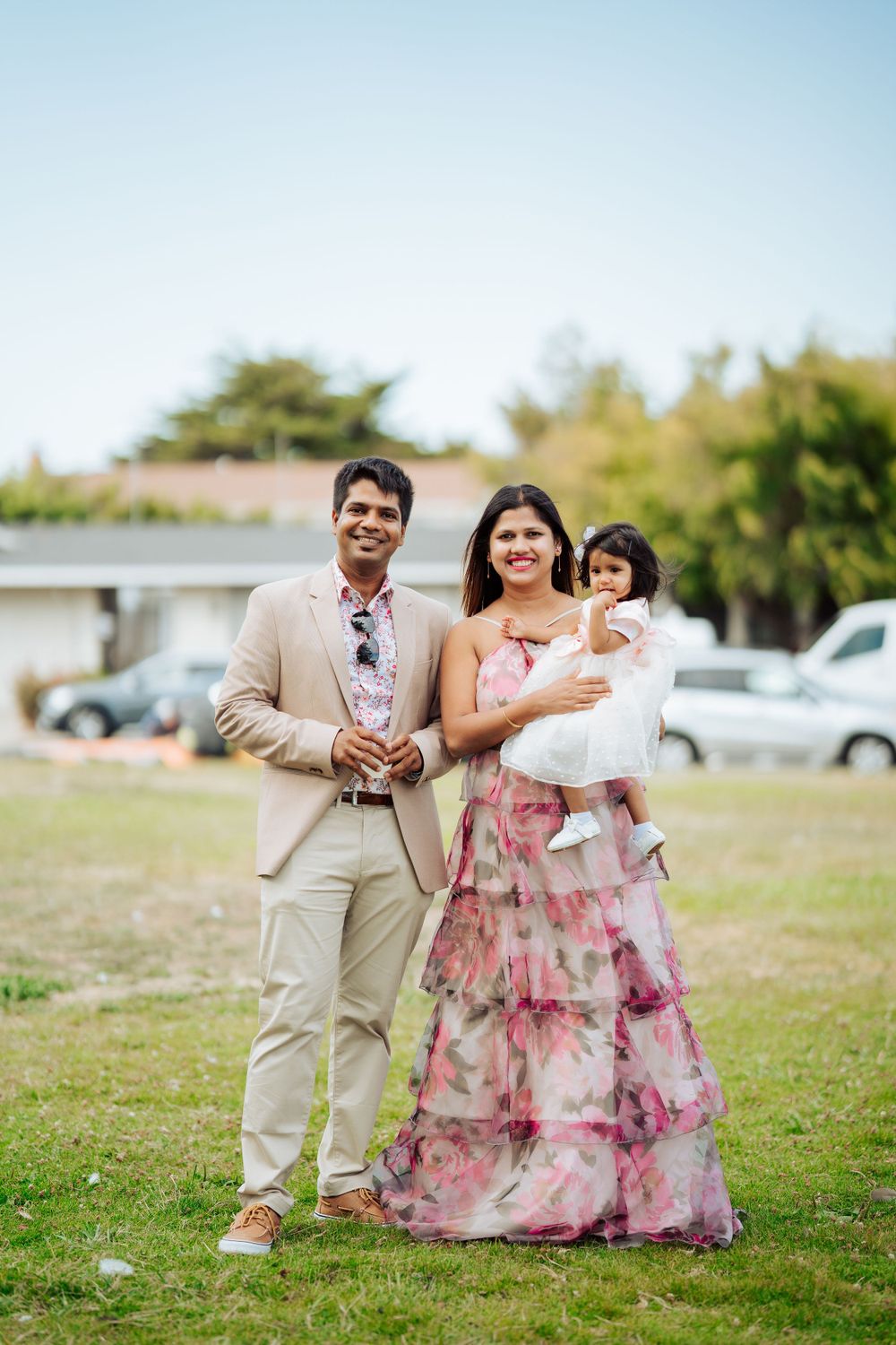 Outdoor family portrait in formal wear on a grassy field.