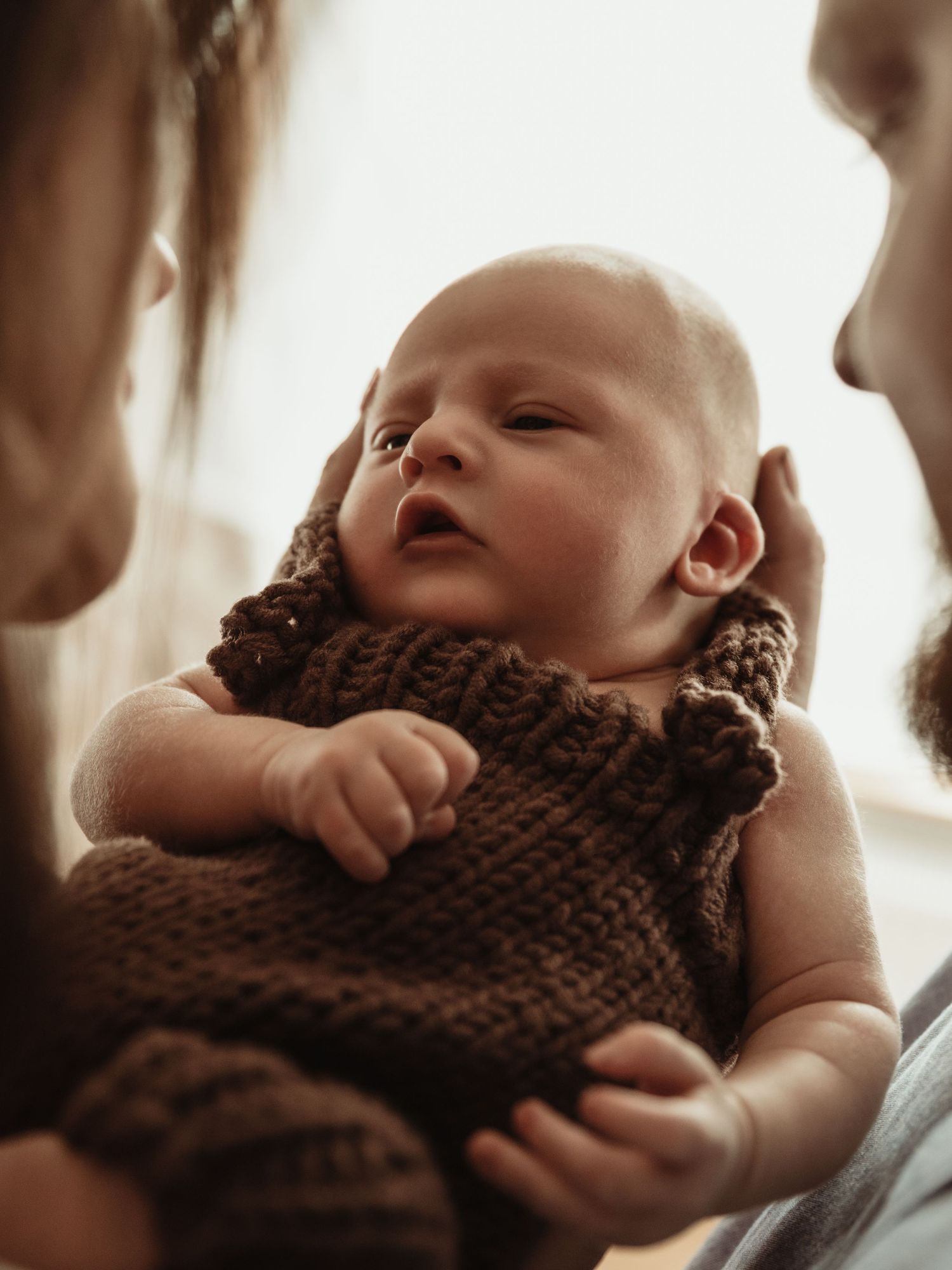 Newborn looks at parents. Image by dmcgphoto.