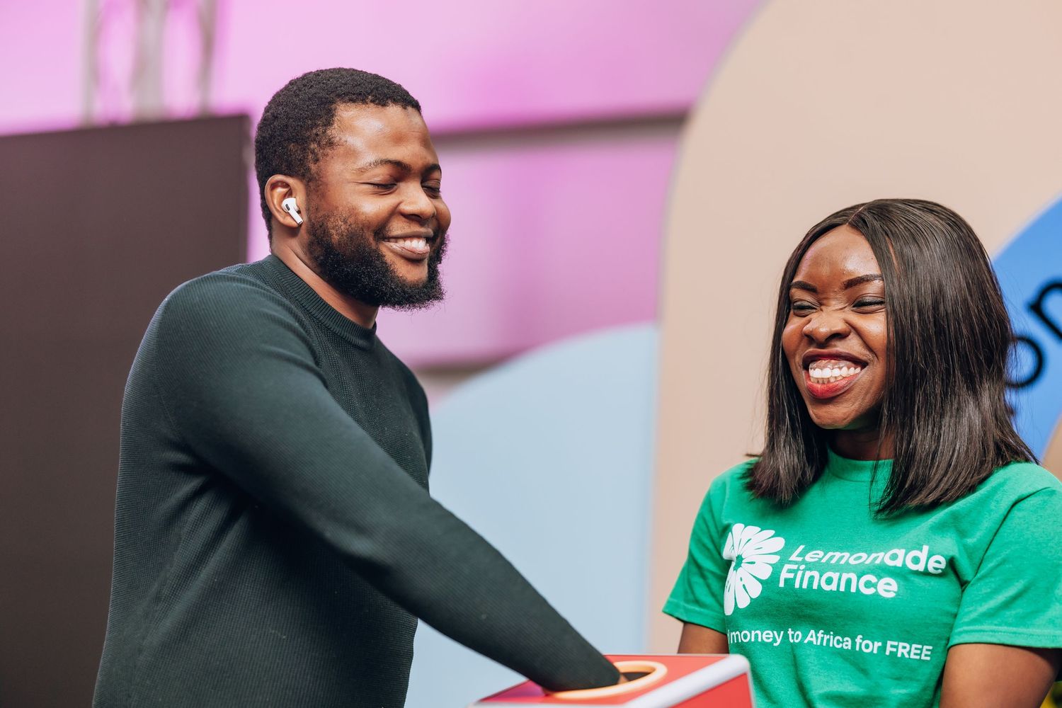 A moment of celebration and sharing between two people at an event with colorful backdrop.