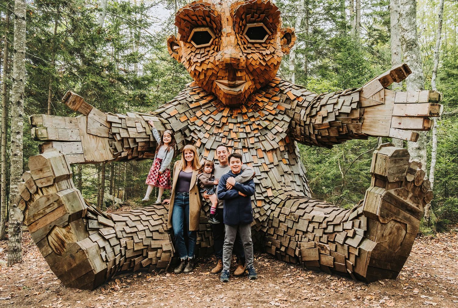 A family gathers for a group shot by one of the trolls at the Maine Botanical Gardens.