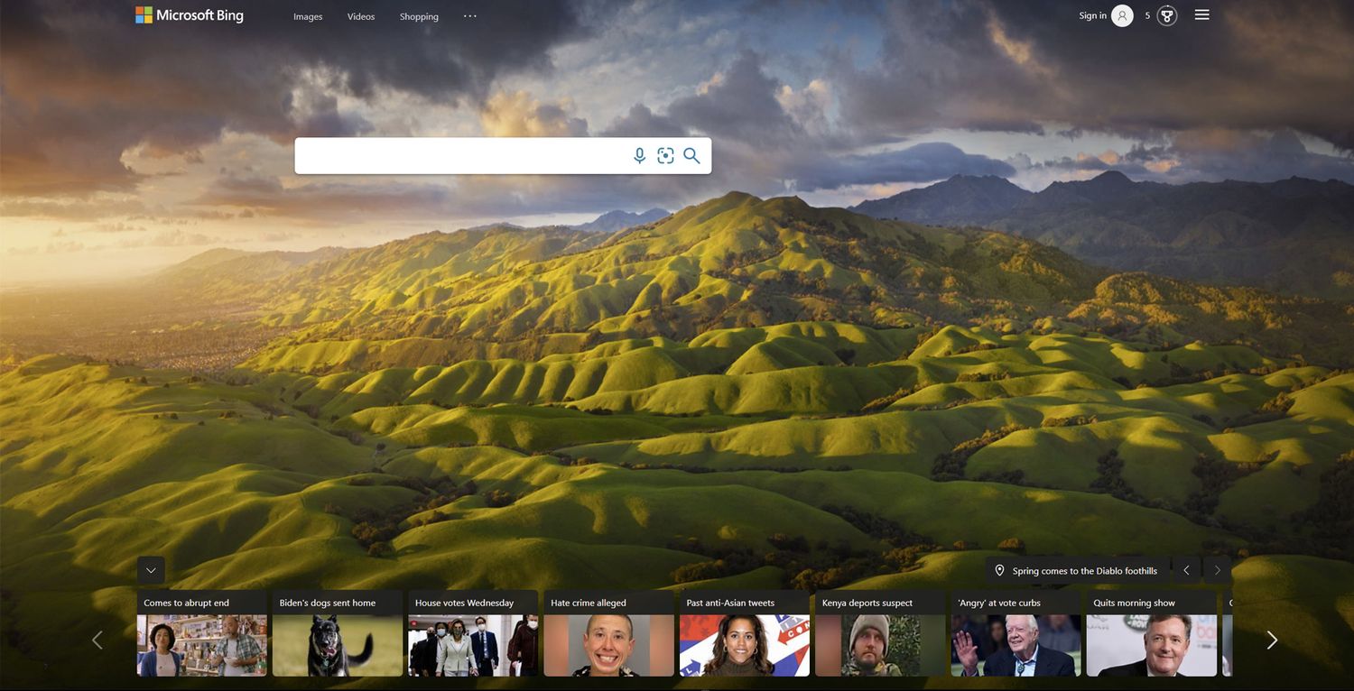 Rolling green hillsides under dramatic sunset clouds with mountains in the distance and search bar interface overlay.